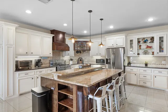 a kitchen with stainless steel appliances a stove a sink a refrigerator a center island and chairs