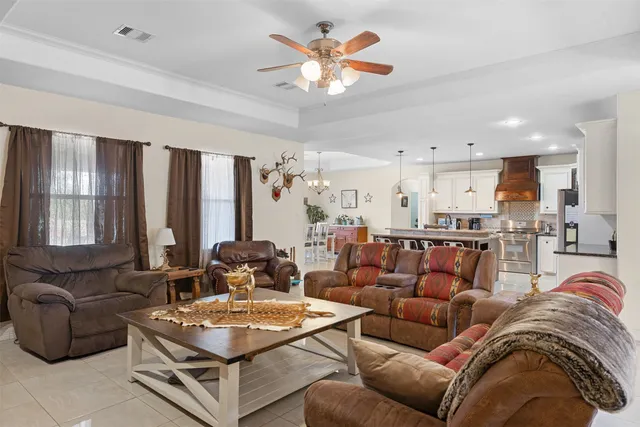 a living room with furniture kitchen view and a large window