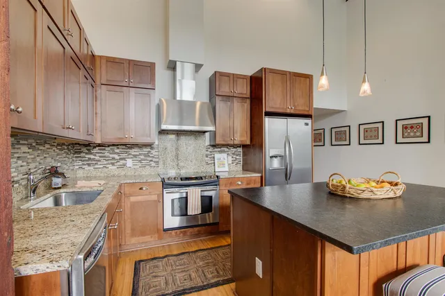 a kitchen with stainless steel appliances granite countertop a sink refrigerator and cabinets