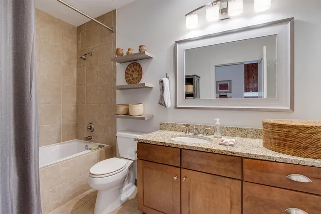 a bathroom with a granite countertop sink vanity mirror bathtub shower and a toilet
