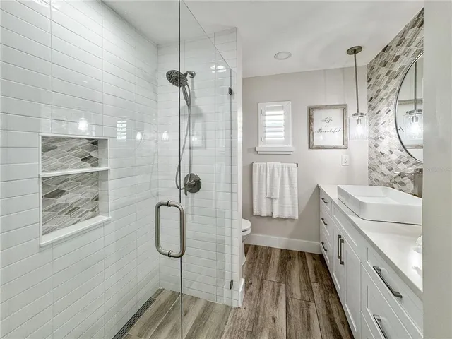 a bathroom with a granite countertop shower a sink and a mirror