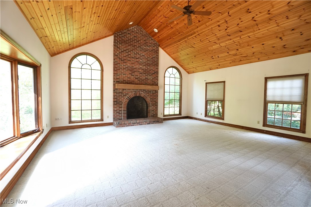 7060 Gates Road Gates Mills, OH 44040 - Photo 8 of 38 Unfurnished great room with plenty of natural light, high vaulted ceiling, a fireplace, light carpet, and wood ceiling