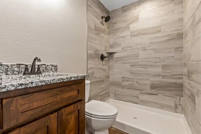 a bathroom with a granite countertop bathtub sink vanity mirror and toilet