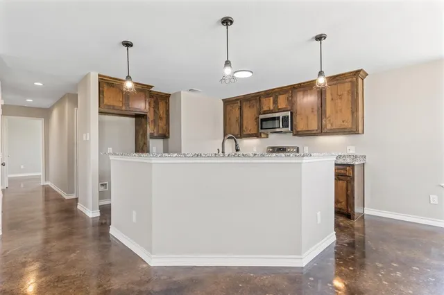 a kitchen with stainless steel appliances granite countertop a refrigerator a oven a sink with a countertop and chairs