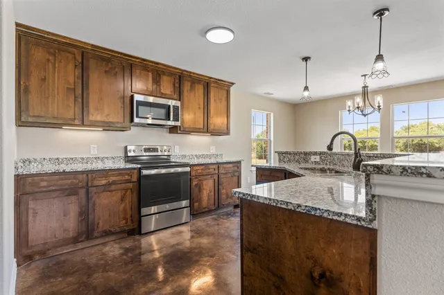 a kitchen with stainless steel appliances granite countertop a sink stove and microwave
