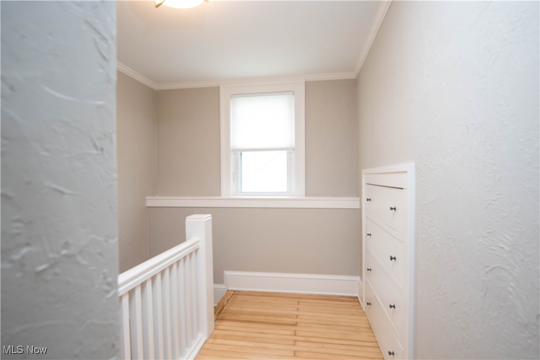 7003 Brecksville Road Independence, OH 44131 - Photo 16 of 35 Hallway featuring crown molding, a textured wall, and light wood finished floors