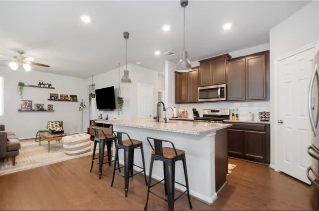 a kitchen with refrigerator a stove and a sink with wooden cabinets