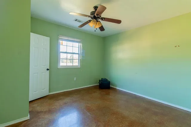 an empty room with a window and a ceiling fan