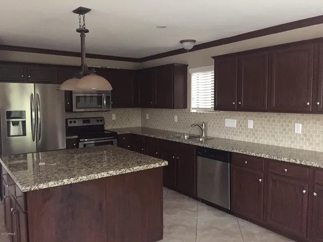 a kitchen with kitchen island granite countertop a sink a counter space appliances and cabinets