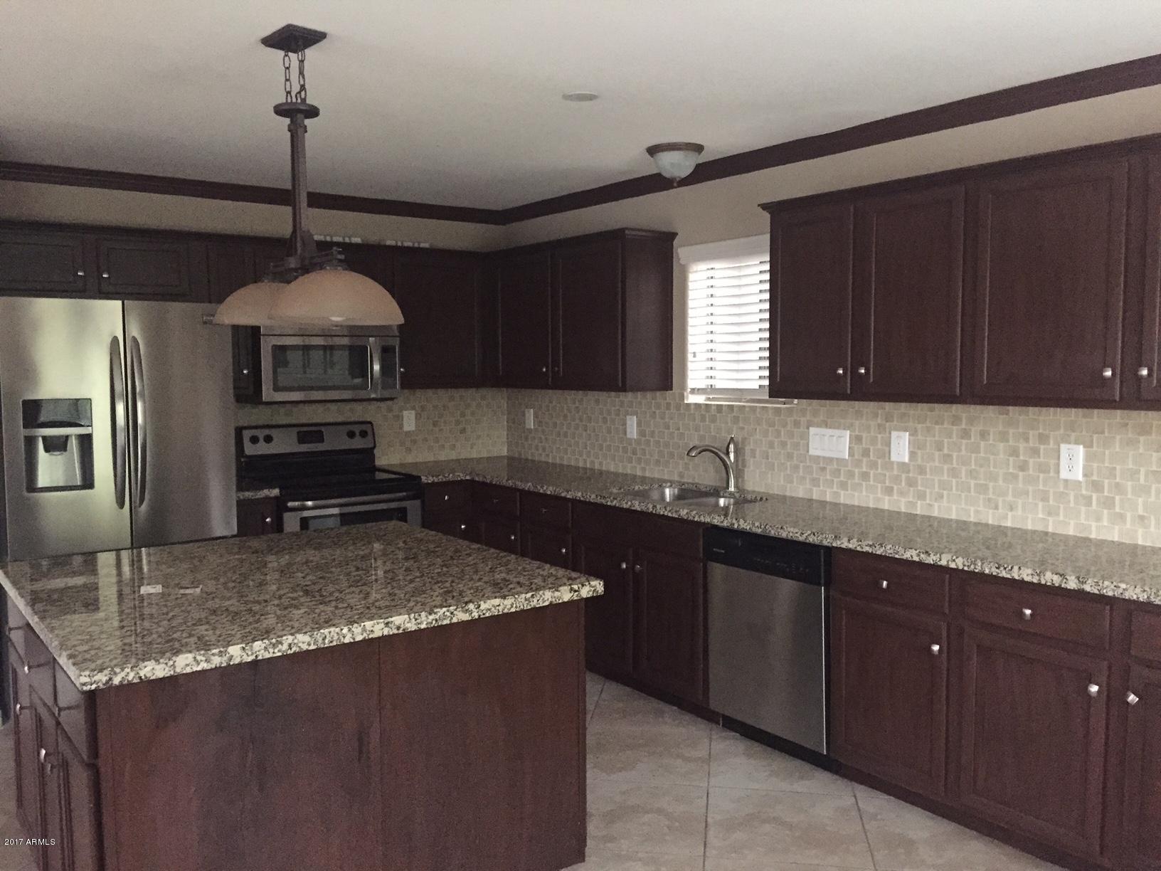 a kitchen with kitchen island granite countertop a sink a counter space appliances and cabinets
