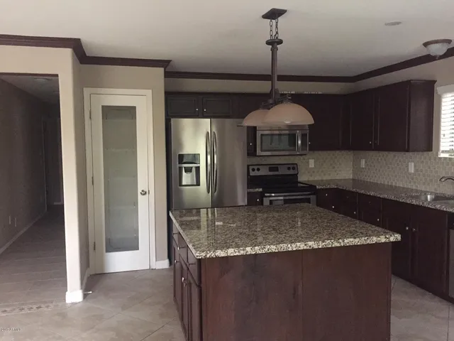 a kitchen with kitchen island granite countertop a sink a counter top space and cabinets