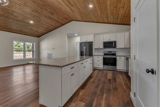 a large kitchen with cabinets wooden floor and stainless steel appliances