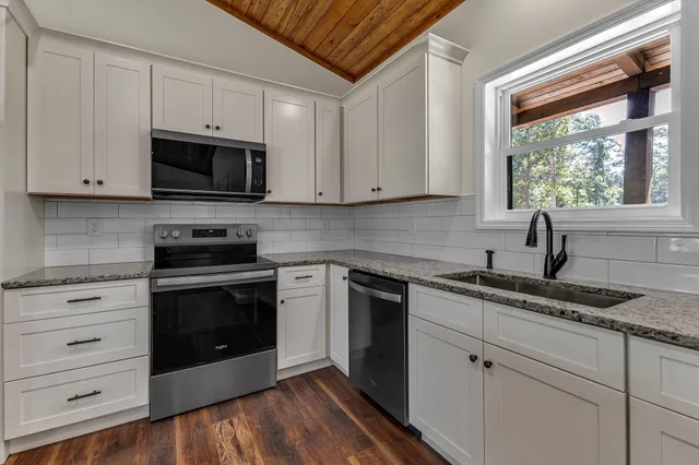 a kitchen with granite countertop white cabinets stainless steel appliances and a sink