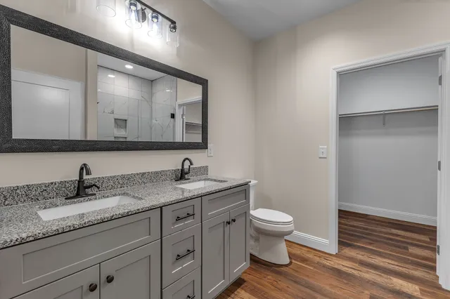 a bathroom with a granite countertop sink a toilet and a large mirror