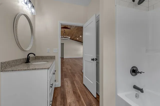 a bathroom with a granite countertop sink a mirror and shower