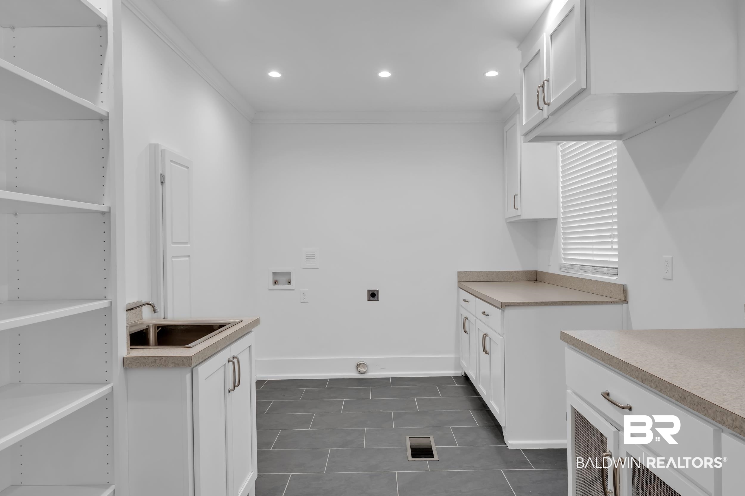 43199 Pine Grove Road Bay Minette, AL 36507 - Photo 38 of 71 Utility room featuring dark gray tile flooring, extensive white cabinetry, light-toned countertops, a utility sink, and recessed lighting