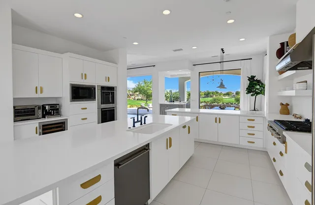 a large white kitchen with kitchen island a sink a stove and a refrigerator