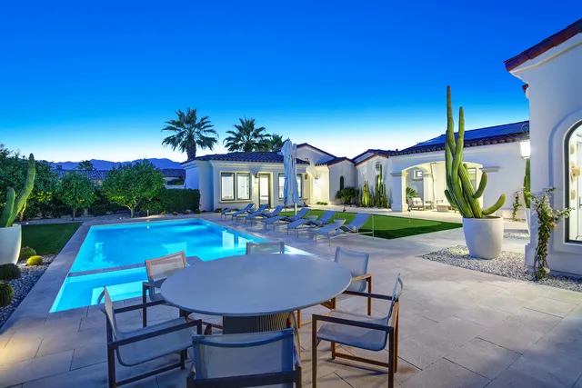 a view of a swimming pool and lounge chairs in back of the house