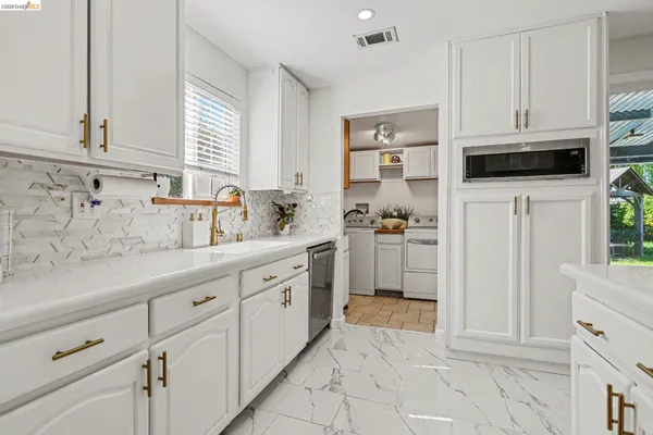 a kitchen with granite countertop white cabinets and stainless steel appliances