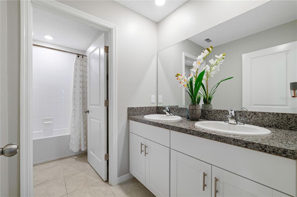 9448 Lemon Drop Loop Ruskin, FL 33573 - Photo 12 of 28 a bathroom with a granite countertop sink a mirror and a shower