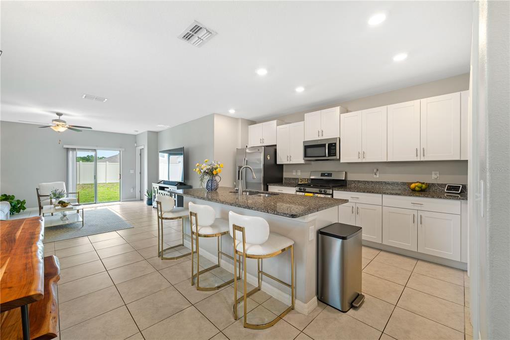 9448 Lemon Drop Loop Ruskin, FL 33573 - Photo 5 of 28 a large kitchen with stainless steel appliances lots of white cabinets a dining table and chairs