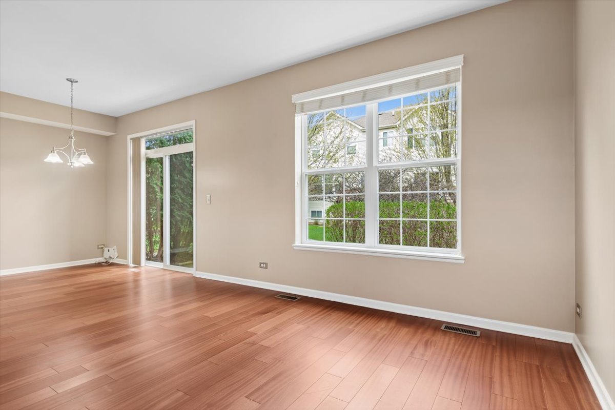 9965 Cummings Street Huntley, IL 60142 - Photo 3 of 23 a view of an empty room with wooden floor and a window