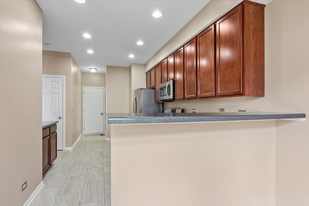 9965 Cummings Street Huntley, IL 60142 - Photo 5 of 23 a view of a refrigerator a kitchen island wooden cabinets and a window
