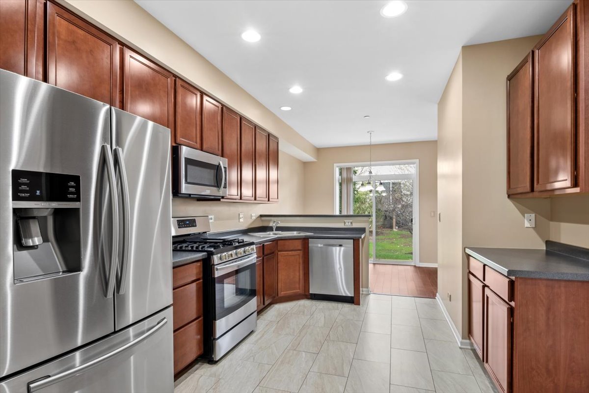9965 Cummings Street Huntley, IL 60142 - Photo 7 of 23 a kitchen with stainless steel appliances granite countertop a refrigerator a sink a stove top oven and a refrigerator