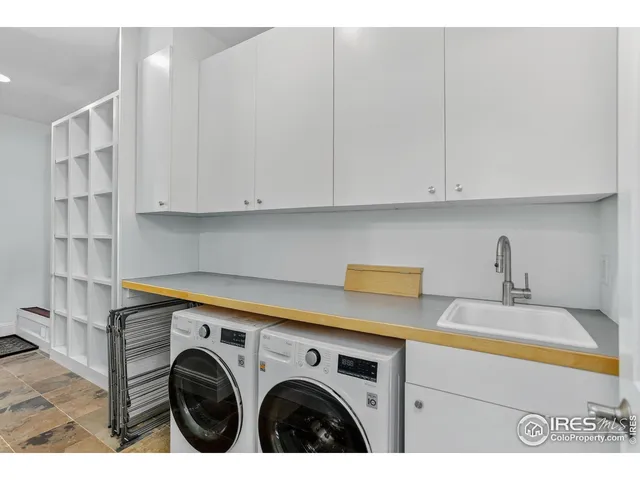 a utility room with stainless steel appliances white cabinets and a sink