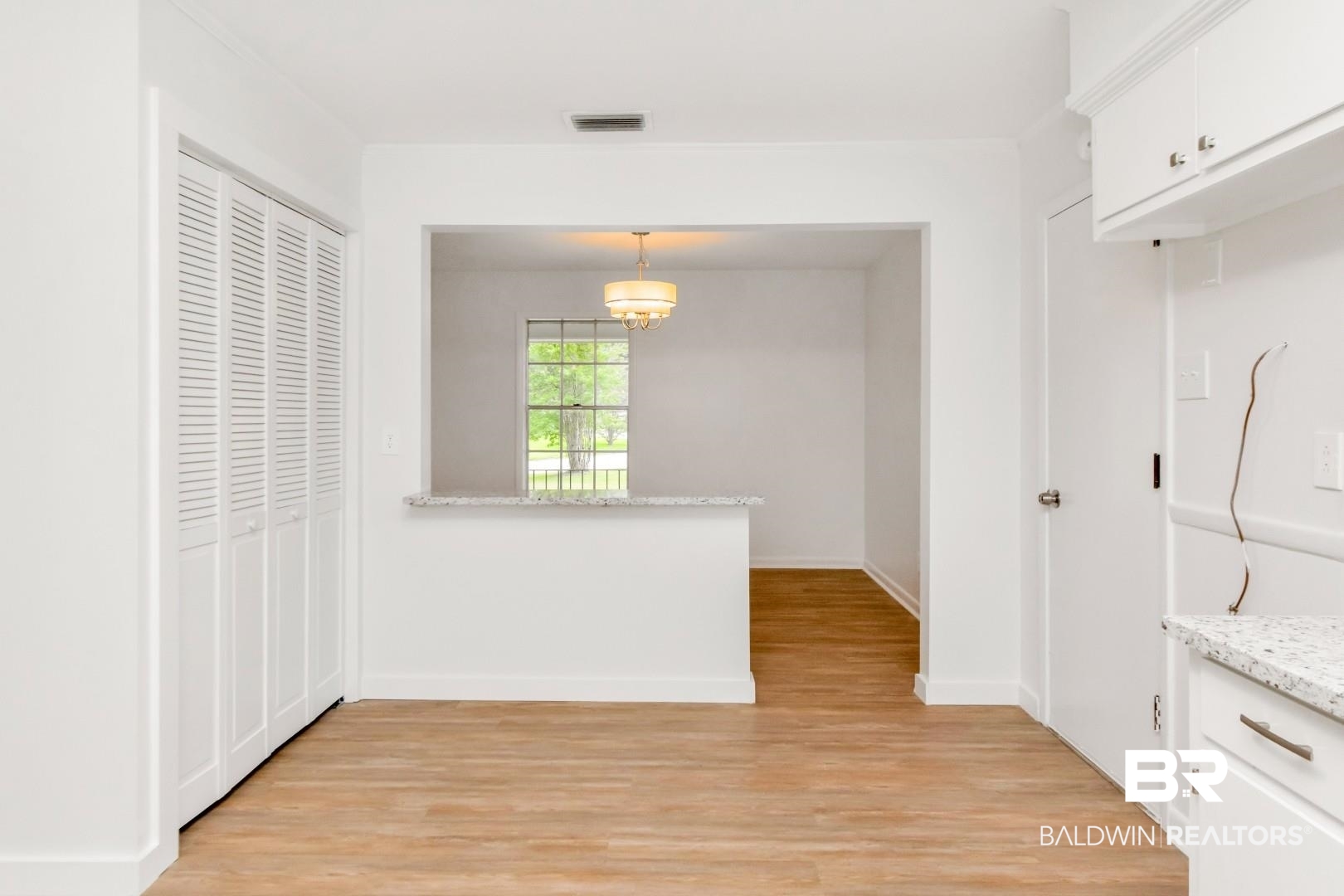 5217 Perin Road Mobile, AL 36693 - Photo 20 of 45 Bright interior with wood-finish flooring, white bifold louvered doors, and a pass-through window with a light-toned countertop