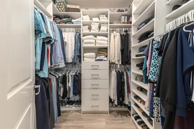 a view of walk in closet with clothes and shoes