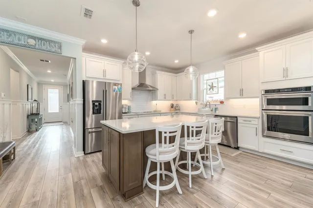 a kitchen with stainless steel appliances kitchen island granite countertop a wooden floor and white cabinets