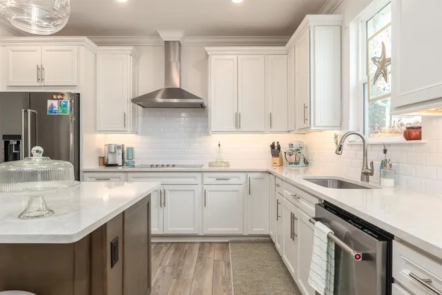 a kitchen with a sink dishwasher a stove and white cabinets