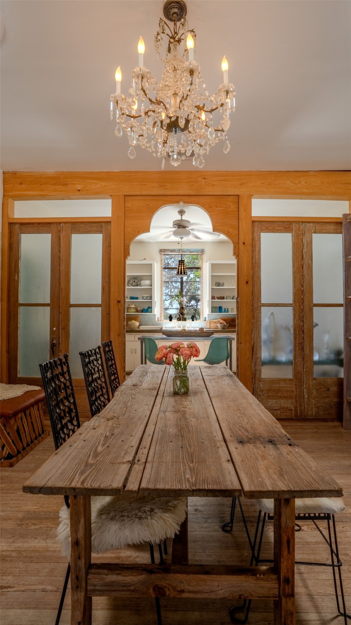 1294 Crabapple Road Blanco, TX 78606 - Photo 9 of 38 Ornate crystal chandelier illuminates a rustic wood dining table, separating a bright kitchen space
