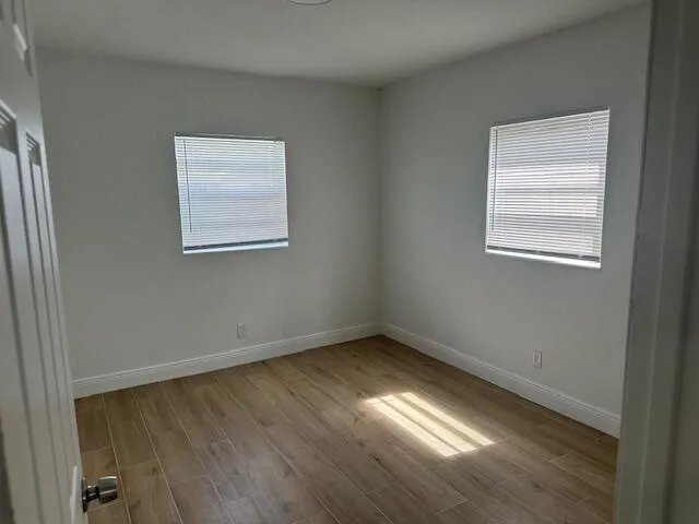 a view of an empty room with wooden floor and a window