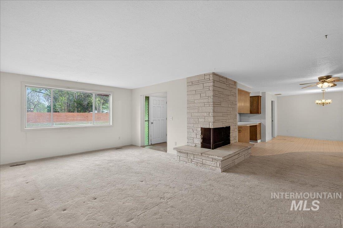 10035 W Lane Boise, ID 83709 - Photo 11 of 32 Unfurnished living room featuring light colored carpet, a ceiling fan, a textured ceiling, and a stone fireplace