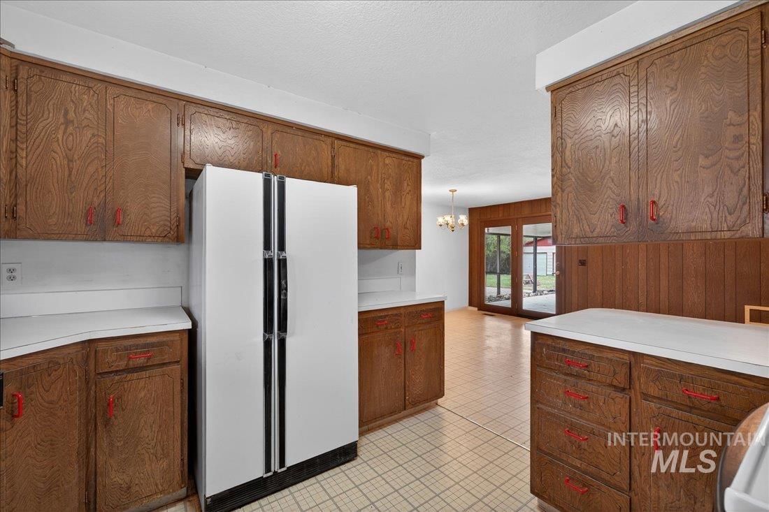 10035 W Lane Boise, ID 83709 - Photo 13 of 32 Kitchen with wooden walls, light countertops, freestanding refrigerator, a chandelier, and light floors