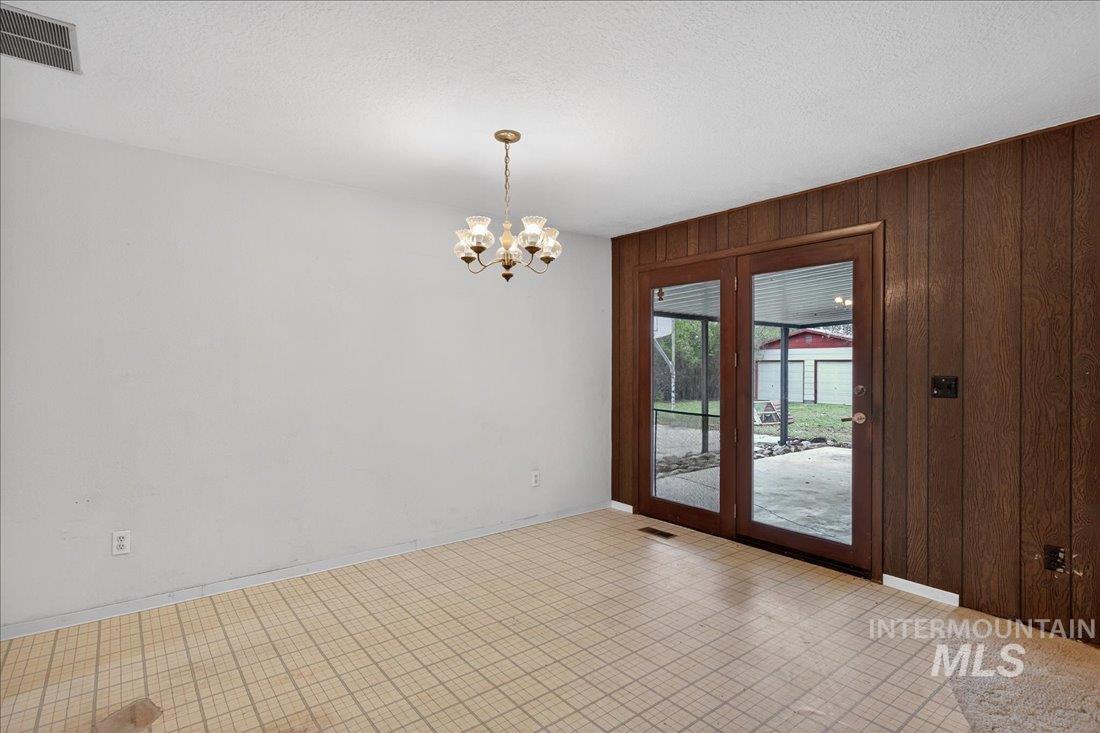 10035 W Lane Boise, ID 83709 - Photo 15 of 32 Spare room featuring a chandelier, wood walls, and a textured ceiling