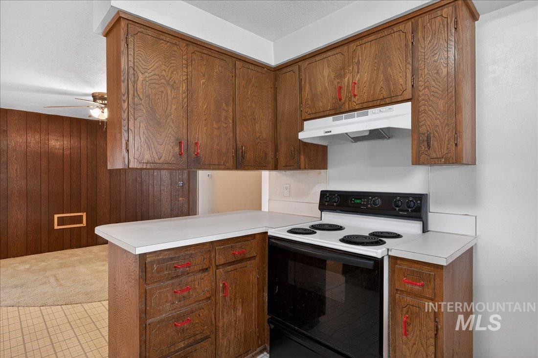 10035 W Lane Boise, ID 83709 - Photo 17 of 32 Kitchen featuring range with electric cooktop, light countertops, a peninsula, ceiling fan, and wooden walls