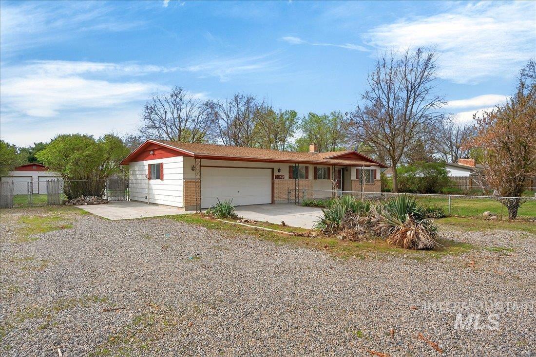 10035 W Lane Boise, ID 83709 - Photo 4 of 32 Ranch-style house featuring driveway, an attached garage, a chimney, brick siding, and covered porch