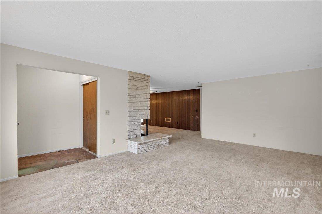 10035 W Lane Boise, ID 83709 - Photo 8 of 32 Unfurnished living room featuring carpet floors, wood walls, and a fireplace
