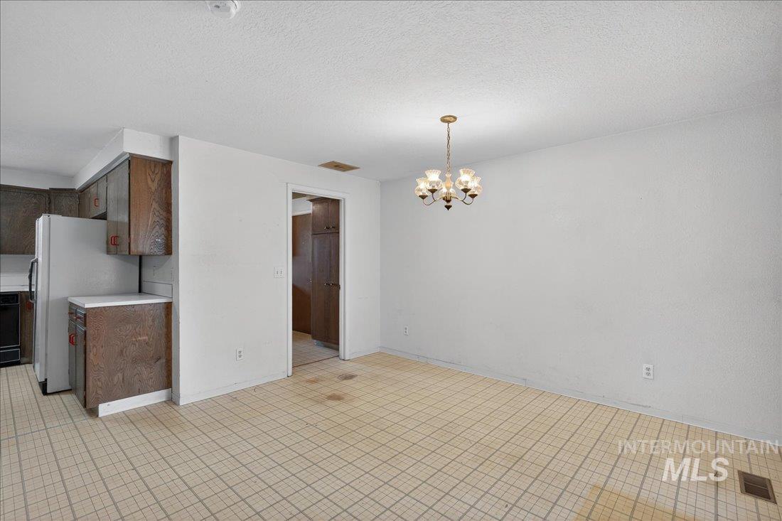 10035 W Lane Boise, ID 83709 - Photo 9 of 32 Unfurnished dining area with hanging lights and a textured ceiling