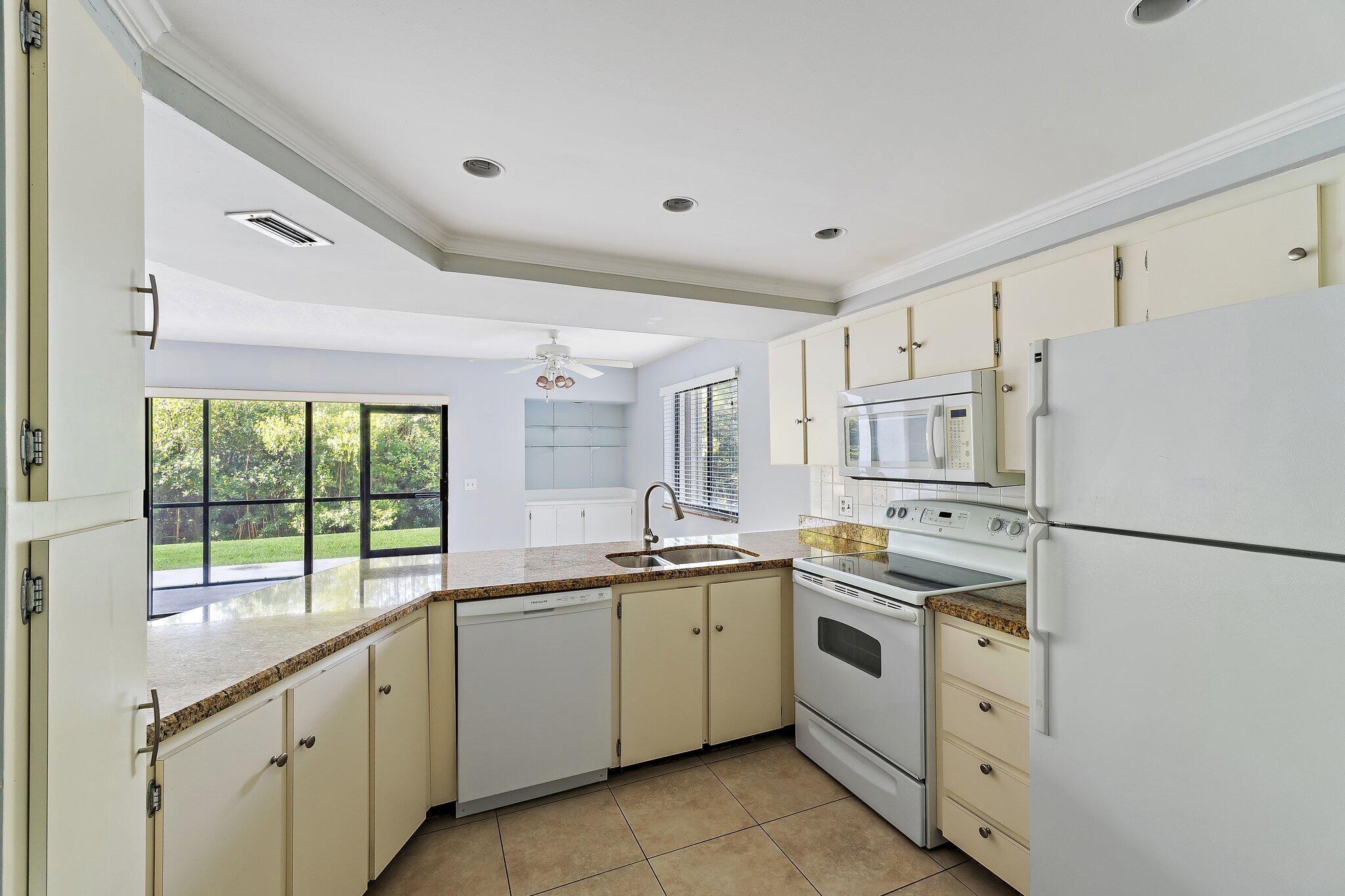 1605 South U Highway, Unit F 106 Jupiter, FL 33477 - Photo 33 of 43 a kitchen with white cabinets and white appliances