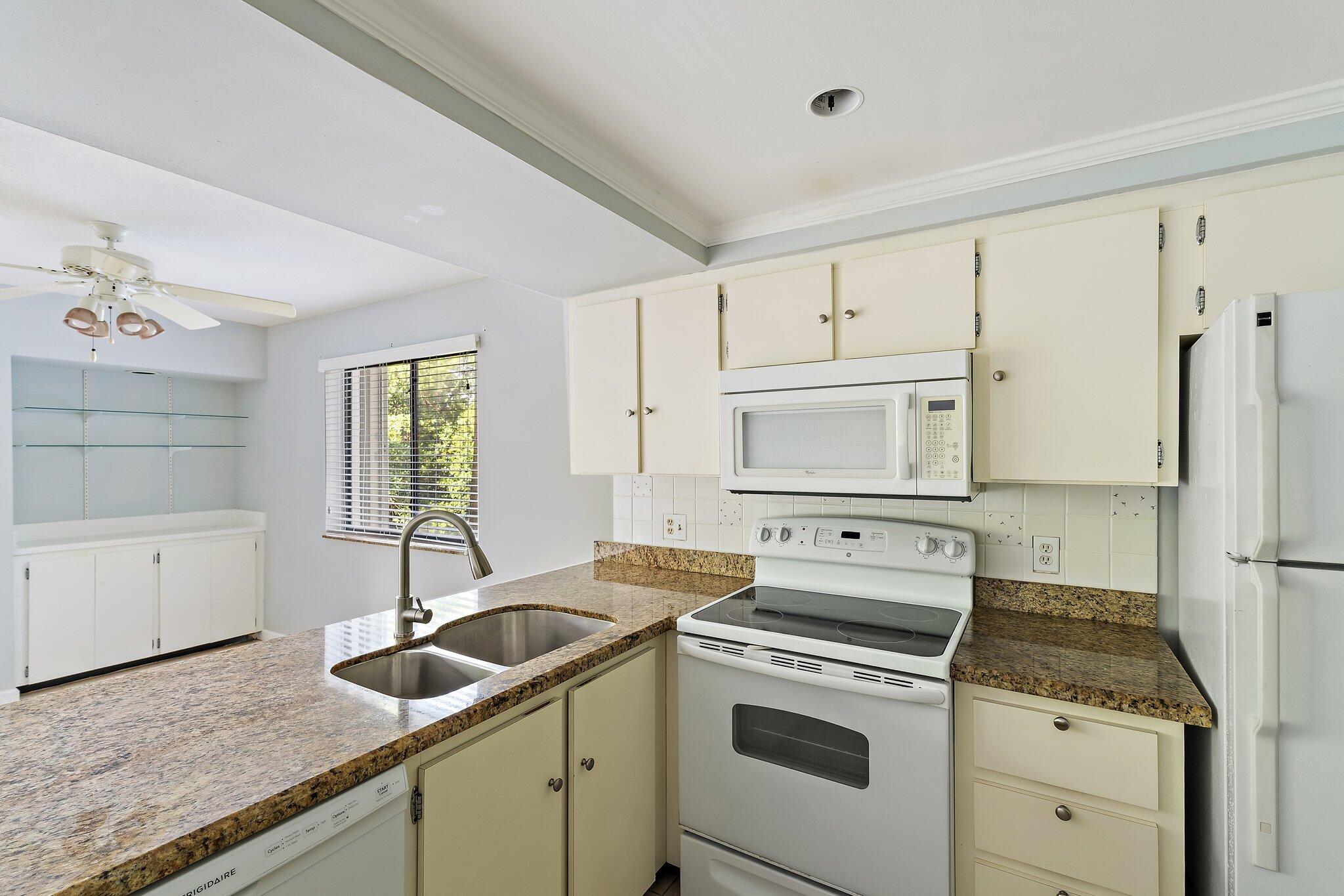 1605 South U Highway, Unit F 106 Jupiter, FL 33477 - Photo 34 of 43 a kitchen with granite countertop a sink stove and refrigerator