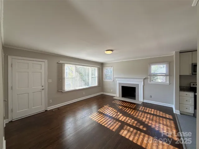 an empty room with windows a fireplace and wooden floor