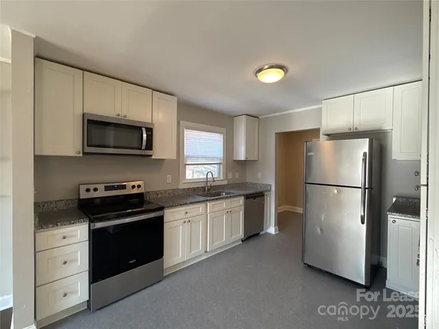 a kitchen with granite countertop a refrigerator stove and microwave