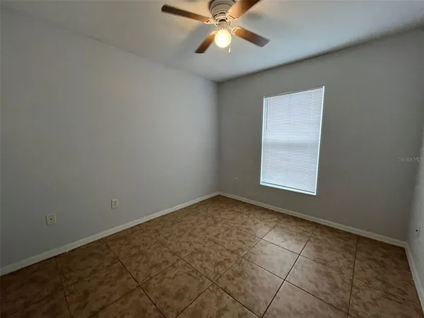 an empty room with a window and a fan