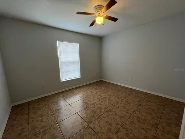 an empty room with a window and a ceiling fan