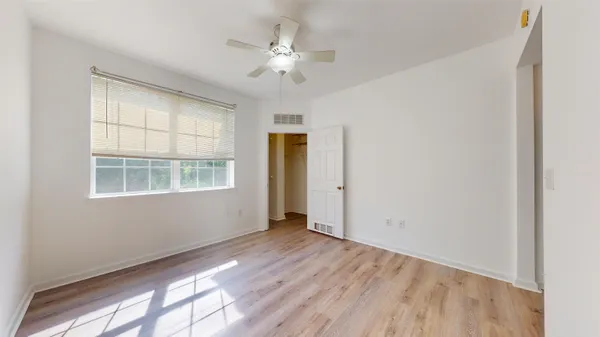 a view of an empty room with a window and wooden floor