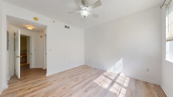 a view of empty room with wooden floor and fan